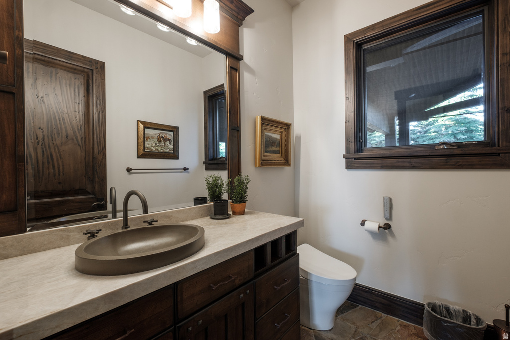 Bathroom featuring a dark wood vanity with a light-toned countertop, an oval vessel sink, and a dark bronze faucet