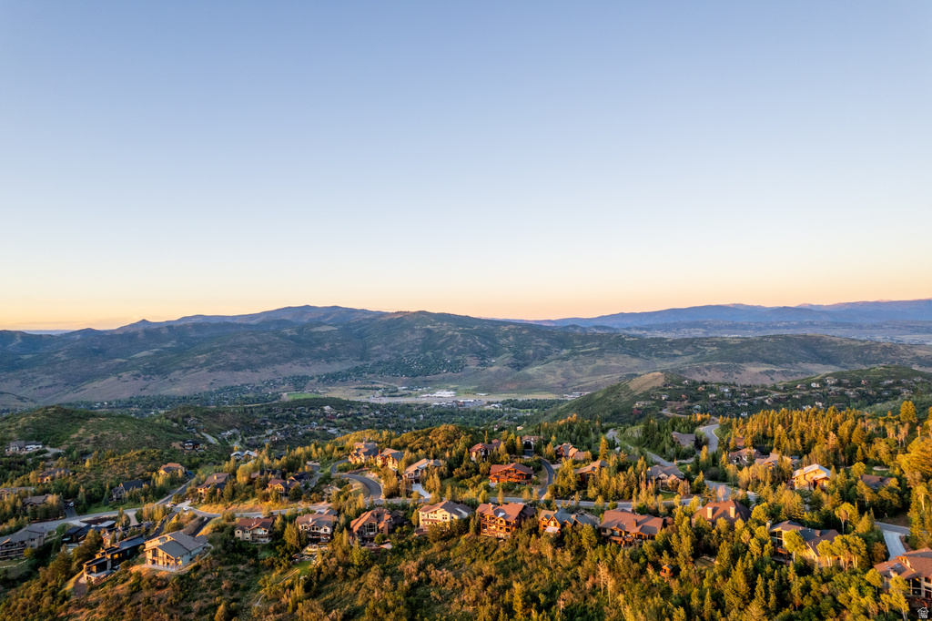 Expansive mountain terrain surrounding a hillside community featuring numerous residences and mature evergreen trees