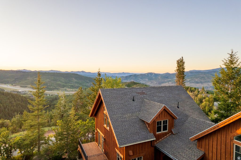 Wood-sided residence featuring a multi-pitch shingle roof and dormer windows