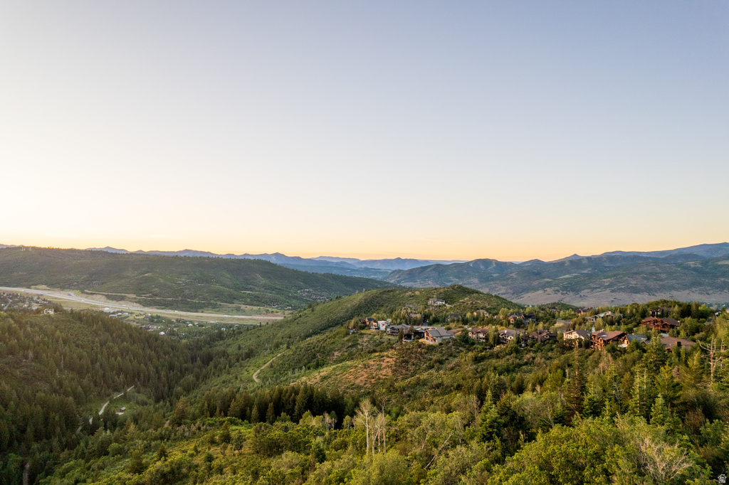 Expansive mountain landscape featuring varied topography, mature evergreen and deciduous trees, and residential structures integrated into the hillside