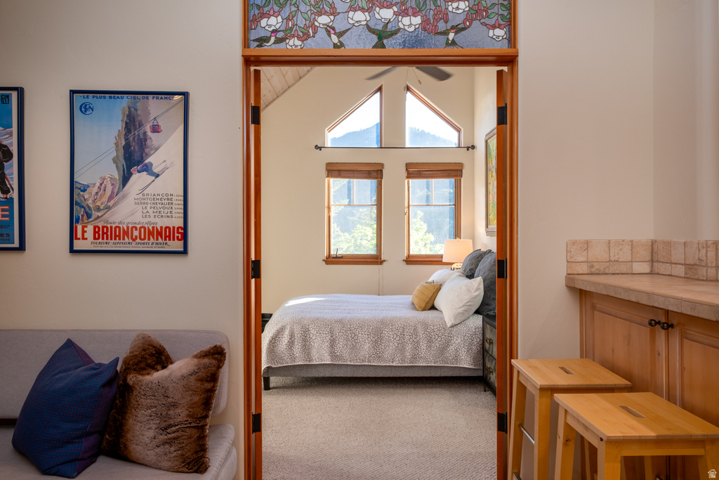Bedroom featuring vaulted ceilings, multiple windows with wood blinds, and a ceiling fan