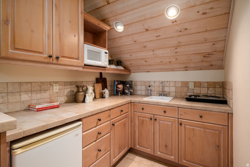 Wood-paneled ceiling with recessed lighting above a functional kitchenette