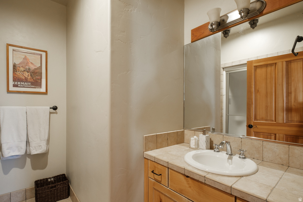 Bathroom vanity featuring a tile countertop, integrated basin, and wood-finish cabinetry