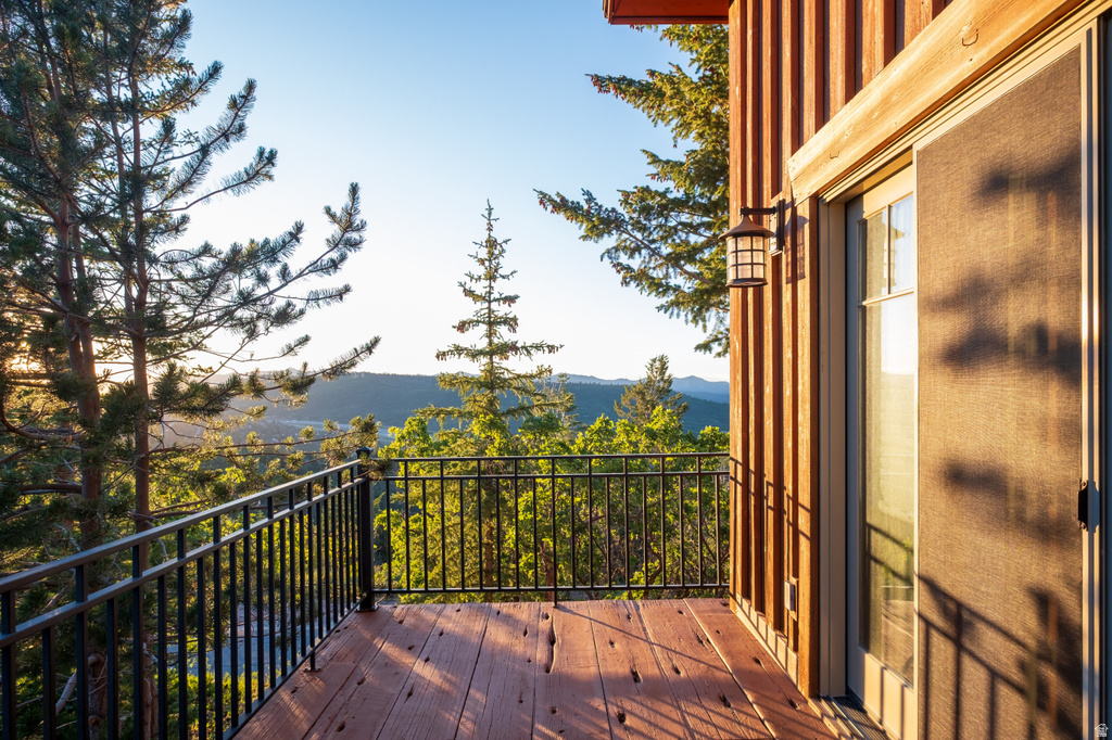 Private balcony with wood-finish decking, black metal railing, and vertical wood siding