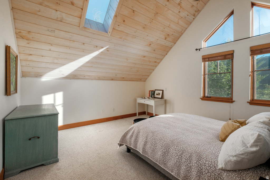 Vaulted ceiling with natural wood paneling, skylight, and multiple windows with wood trim