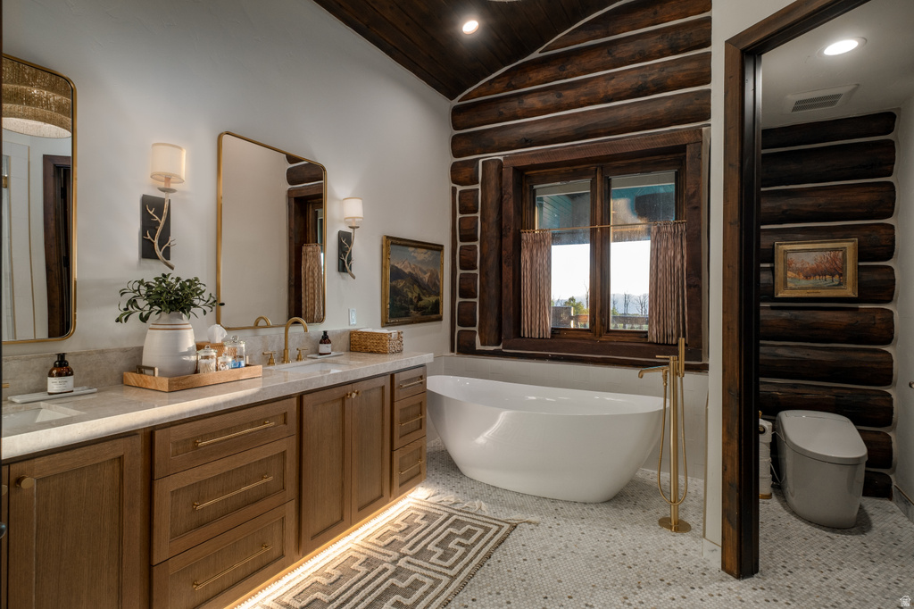 Freestanding soaking tub with a floor-mounted gold-tone faucet, flanked by natural log walls