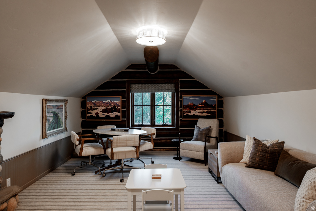 Attic room with sloped ceilings, featuring a dark wood-finish log wall and a window with a patterned shade