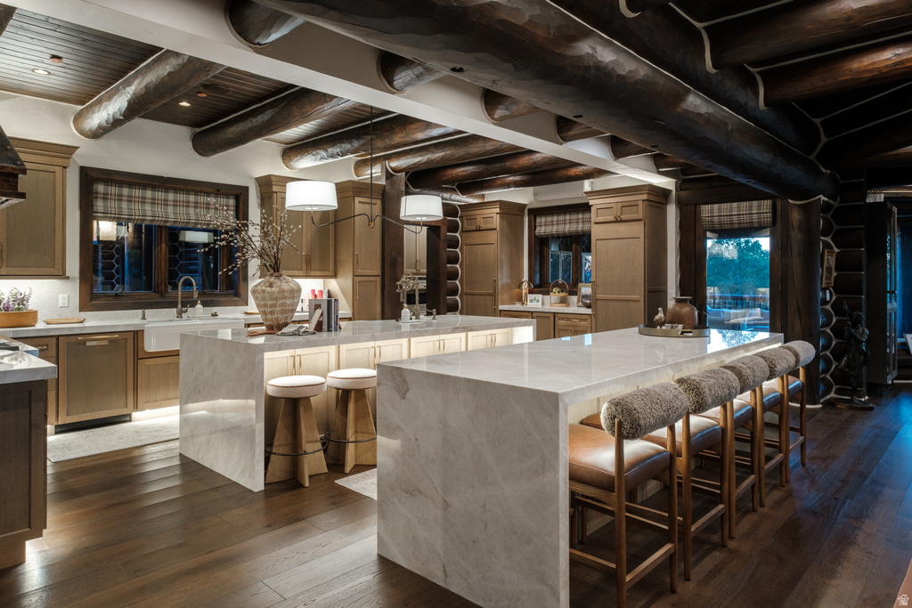 Gourmet kitchen featuring a farmhouse sink, integrated appliances, two waterfall-edge islands, and dark wood-finish flooring
