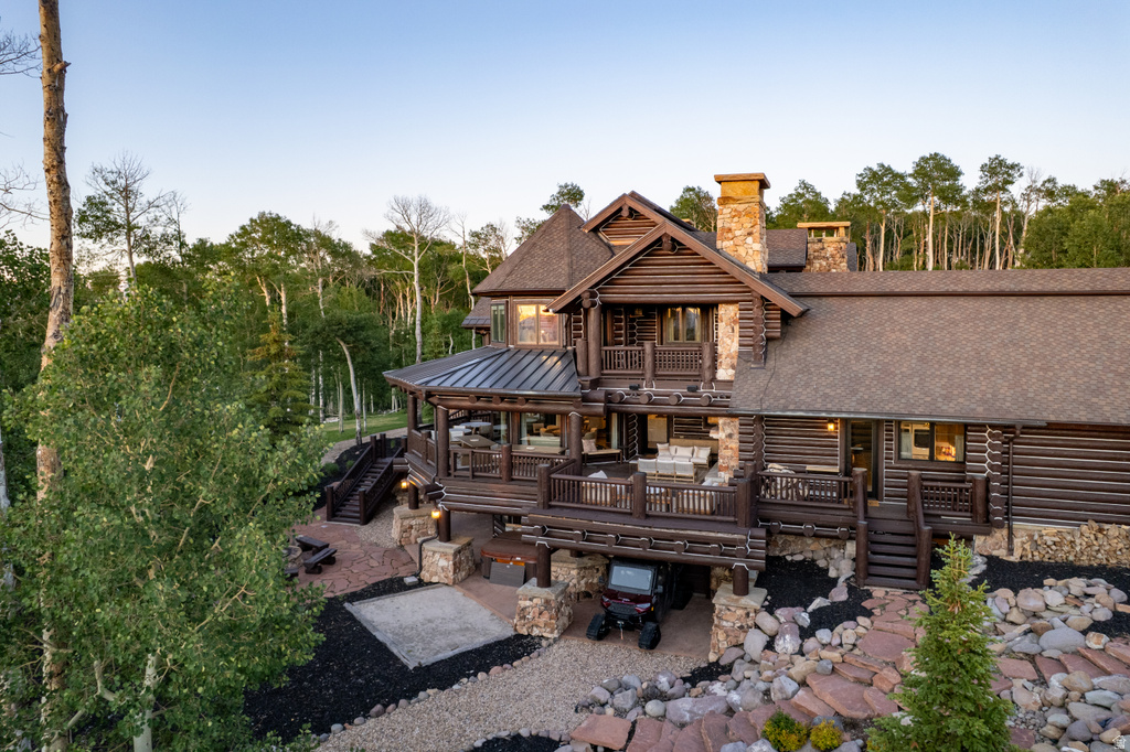 Log home exterior featuring multiple stone chimneys, expansive multi-level decking, and a gravel driveway