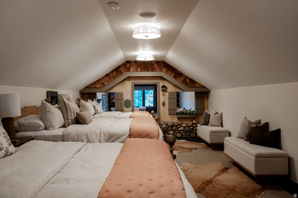 Sloped ceiling room featuring recessed lighting, a window with exterior shutters, a stone-finish wall detail, and built-in upholstered benches