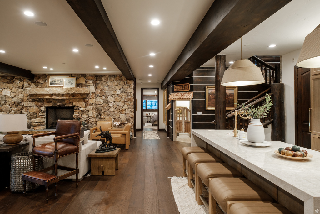 Spacious interior featuring wide plank wood-finish flooring, a stone-clad fireplace, and exposed ceiling beams