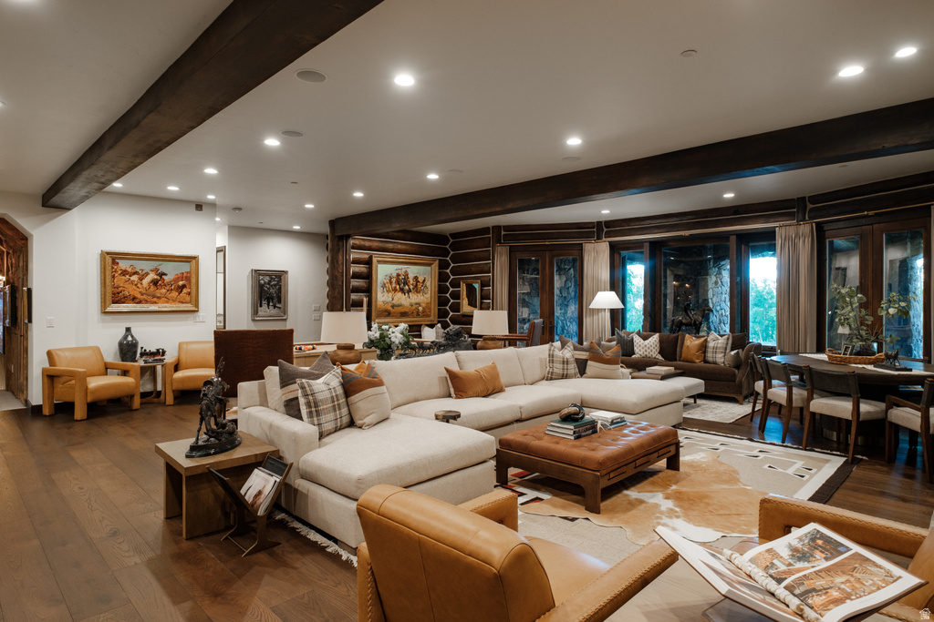 Spacious living area featuring exposed wood beams, recessed lighting, wood-finish flooring, and expansive window walls