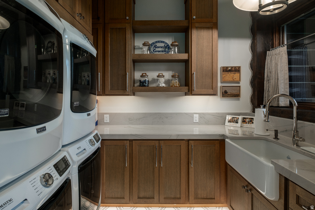 Laundry room featuring a white farmhouse sink, chrome gooseneck faucet, light grey countertops, wood-finish cabinetry, and open shelving