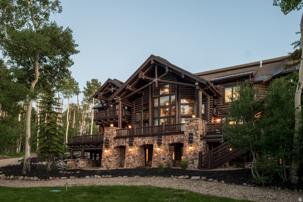 Expansive log cabin architecture featuring a stone foundation, multiple balconies, and abundant windows