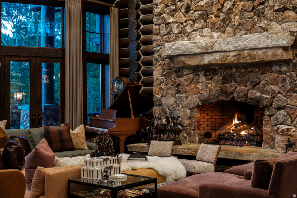 Expansive great room featuring a floor-to-ceiling stone fireplace with a substantial stone mantle and hearth, full-height timber wall detailing, and tall windows with dark wood frames