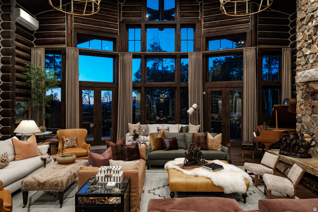 Grand living space featuring a floor-to-ceiling stone fireplace, exposed log walls, and expansive windows