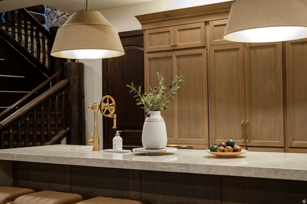 Kitchen island featuring a light-toned stone countertop and a unique brass faucet