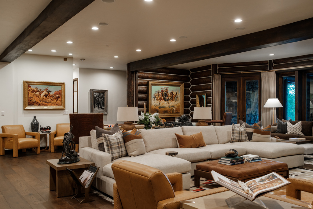 Spacious living area featuring exposed wood beams, recessed lighting, and rich wood-finish flooring
