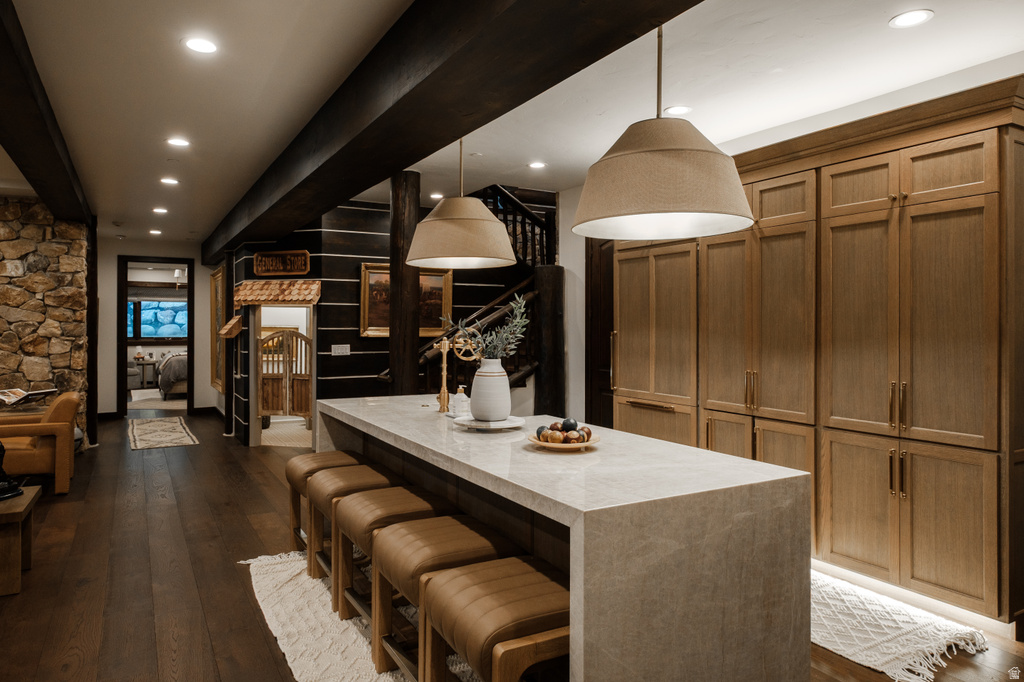 Kitchen island featuring a light-toned countertop, pendant lighting, and integrated seating