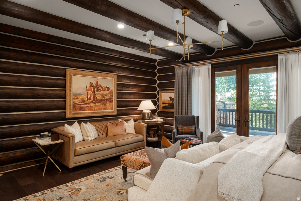 Spacious living area featuring exposed wood beam ceilings, log walls, dark wood-finish flooring, and a large double-door exterior access point