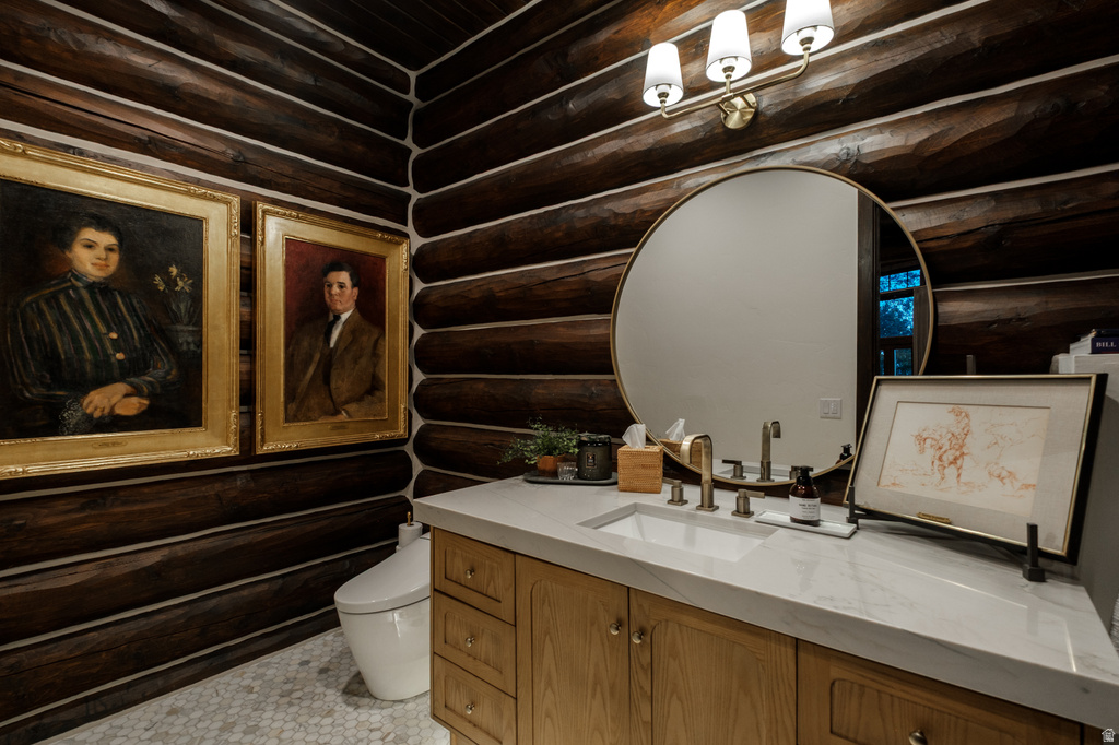 Bathroom vanity featuring light wood cabinetry with brass hardware, a white countertop, and an undermount sink with a brass faucet