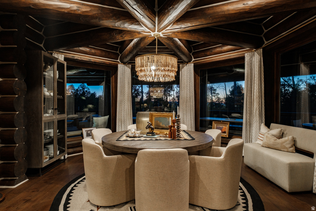 Dining area featuring exposed log and timber beam ceiling, a round wood-finish dining table, and dark wood-finish flooring