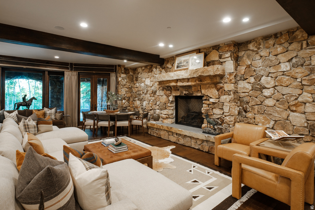 Stone accent wall with a large built-in fireplace, dark wood-finish flooring, recessed lighting, and exposed ceiling beams