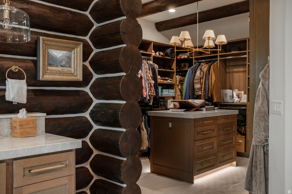 Custom closet featuring a central island with drawers, integrated lighting, and a light-toned countertop