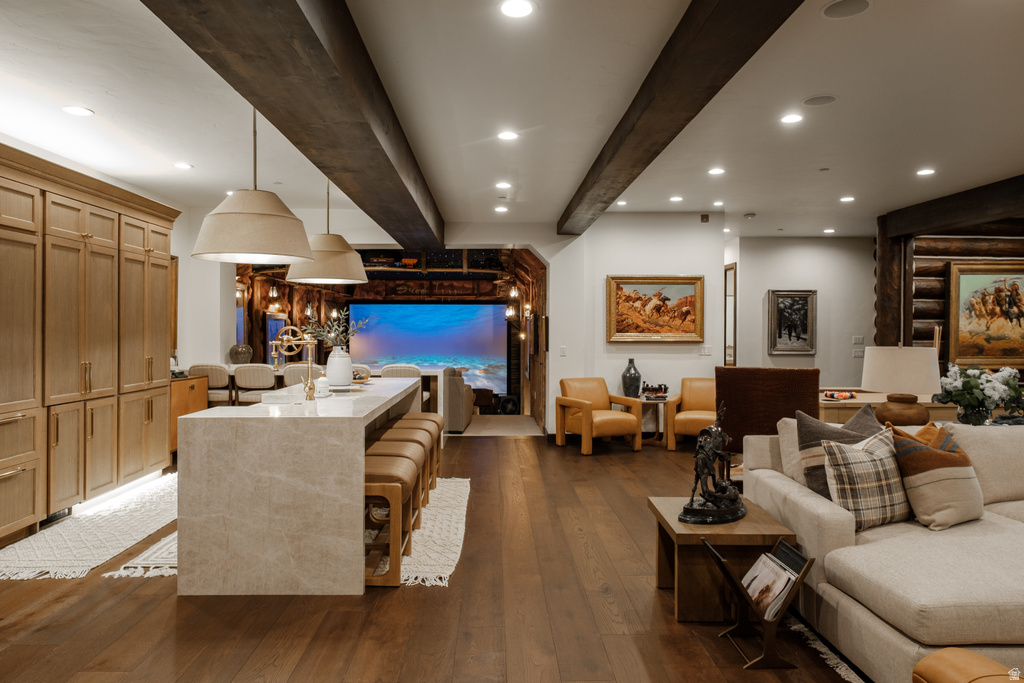 Open-concept living space featuring wood-finish flooring and exposed ceiling beams