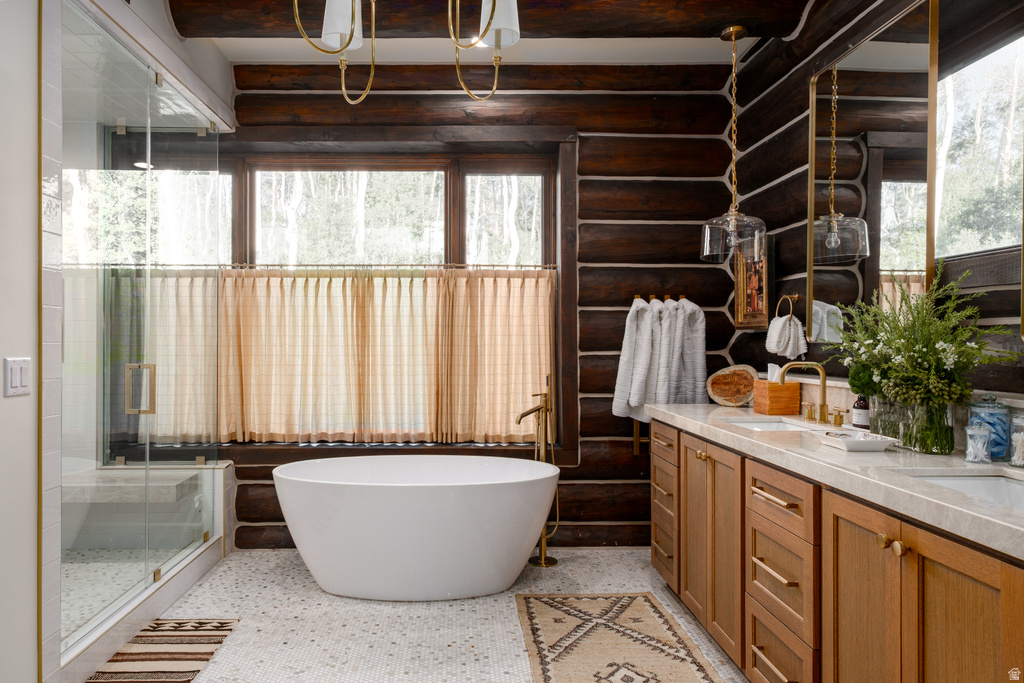 Expansive bathroom featuring dark wood log walls, a freestanding soaking tub, a glass-enclosed shower, a dual vanity with wood cabinetry, and light-colored stone countertops