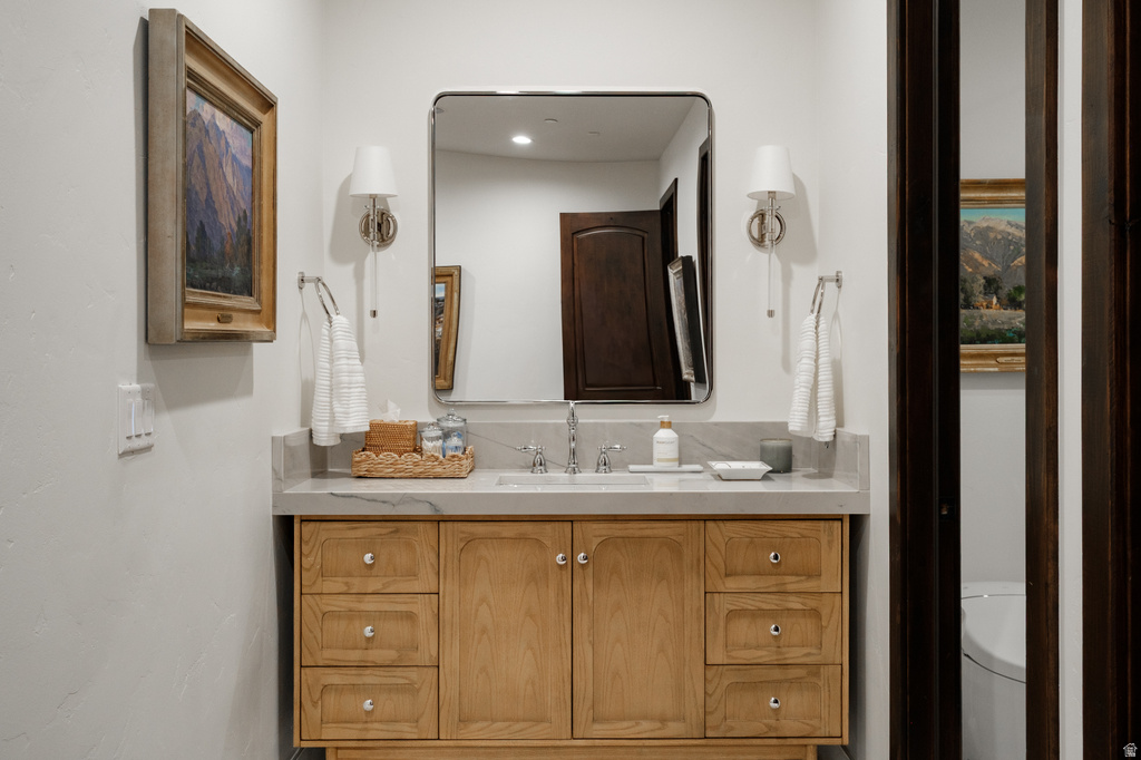 Light wood vanity with integrated sink, stone countertop, and brushed nickel fixtures