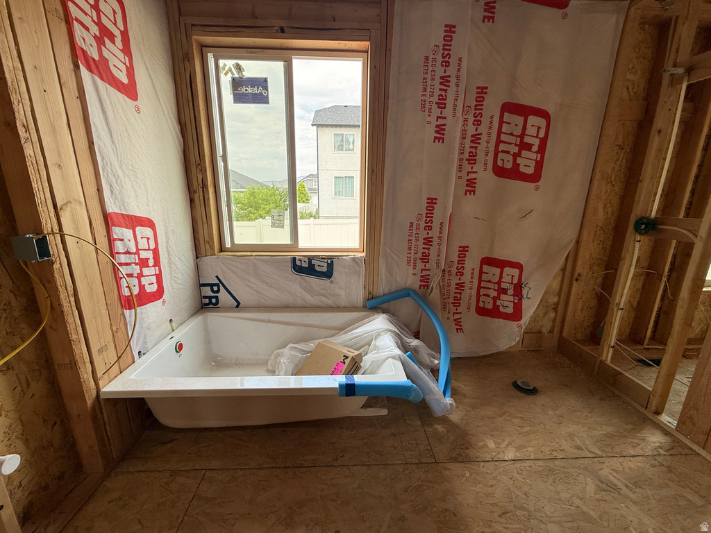 New construction framing featuring a built-in bathtub, a window, and exposed wall studs
