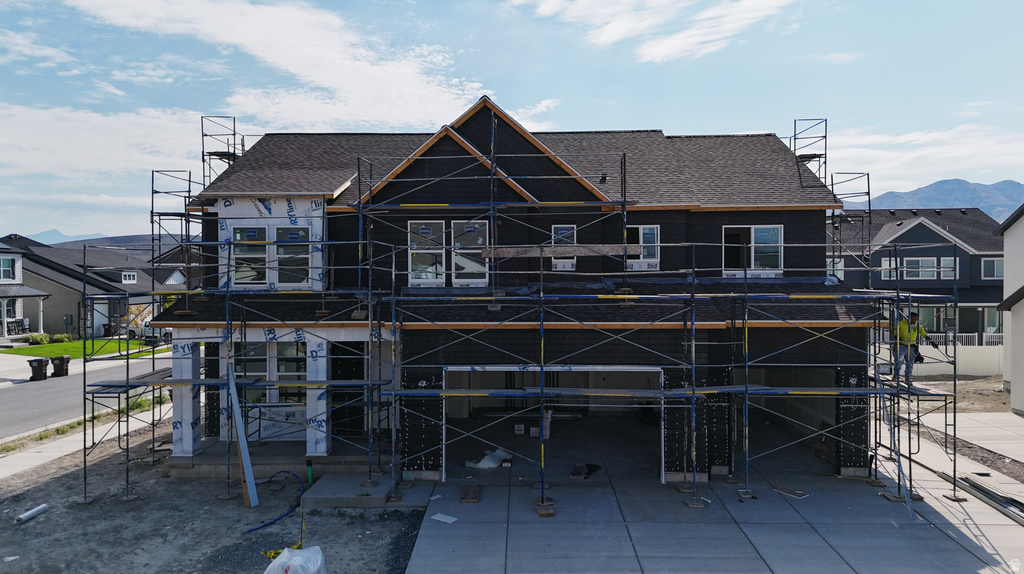 Newly constructed residence featuring a dark shingle roof and a multi-level concrete driveway