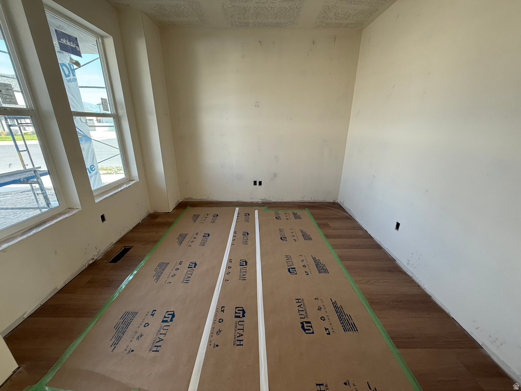 Wood-finish flooring with protective covering, neutral wall finishes, and multiple windows