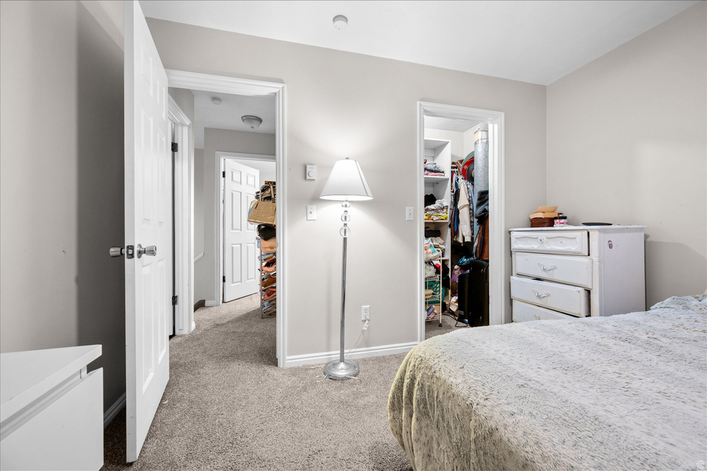 Bedroom featuring light gray wall paint, gray carpet flooring, white trim, and a built-in closet with shelving