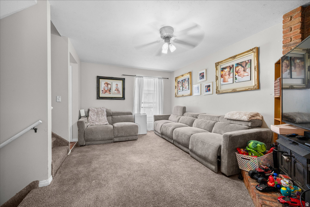 Carpeted living room featuring light gray walls and a ceiling fan