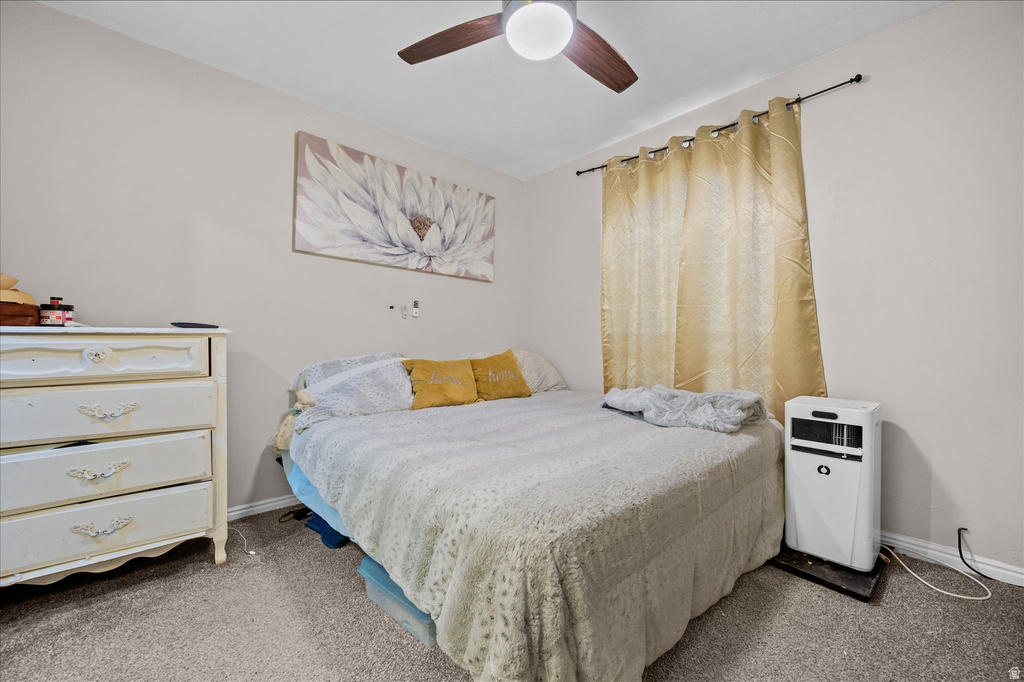 Bedroom featuring neutral wall paint, gray carpet, a ceiling fan with light fixture, and a window with curtain rod