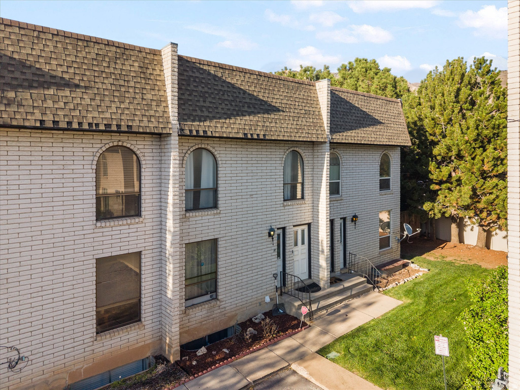 Brick exterior featuring arched windows, pitched shingle roofing, and a front entry with handrails
