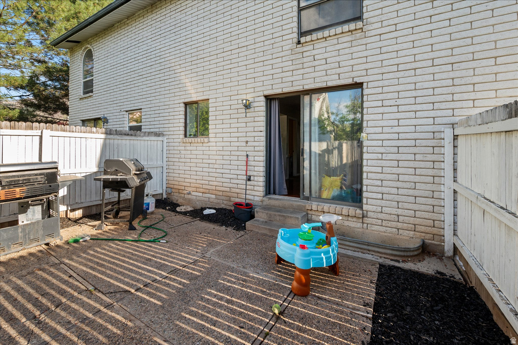 Rear patio featuring a sliding glass door entry, white brick exterior, and full perimeter fencing