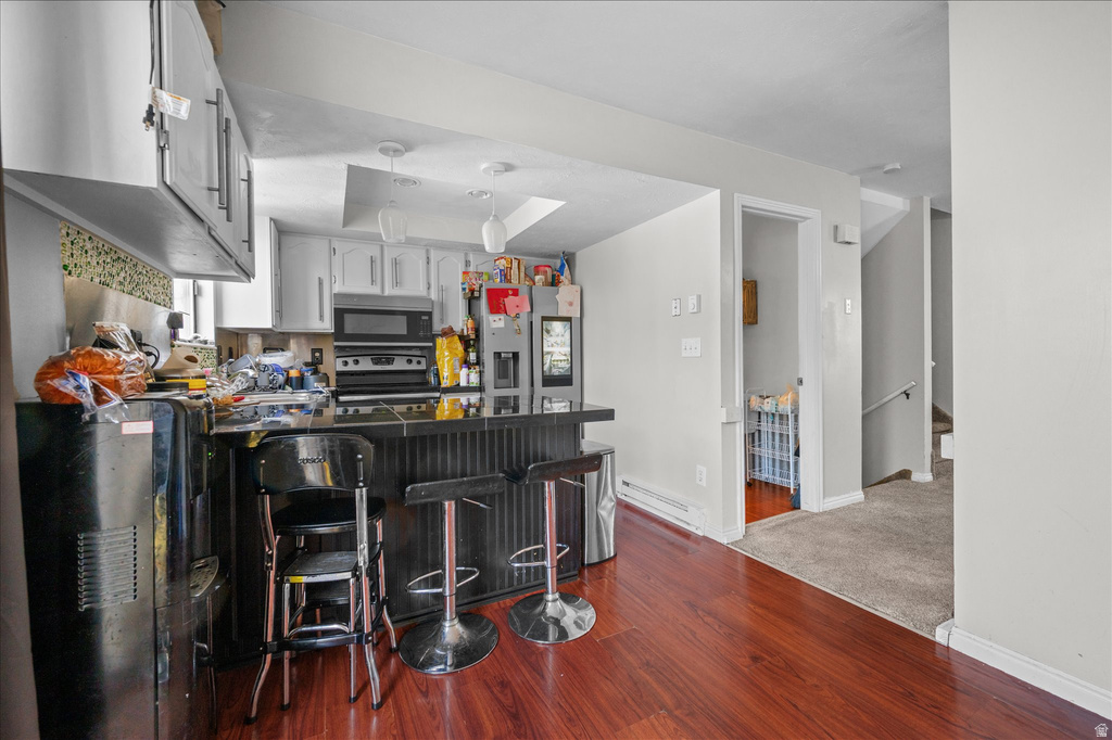 Kitchen featuring wood-finish flooring, a breakfast bar with built-in cabinetry, and gray upper and lower cabinets