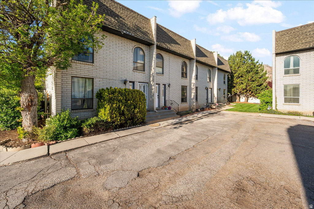Brick exterior with arched windows, mature landscaping, and multi-pane windows