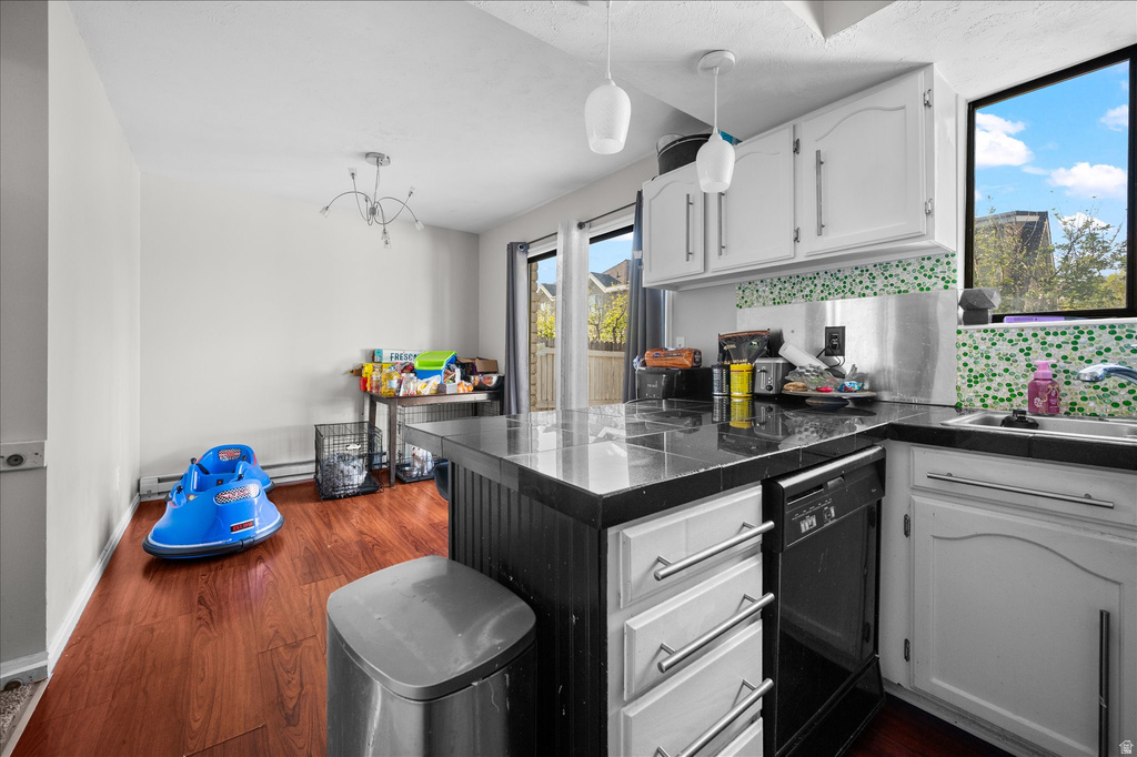 Kitchen featuring white cabinetry with silver hardware, black countertops, and a built-in dishwasher