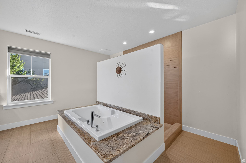 Built-in soaking tub with a stone-finish surround and polished chrome fixtures