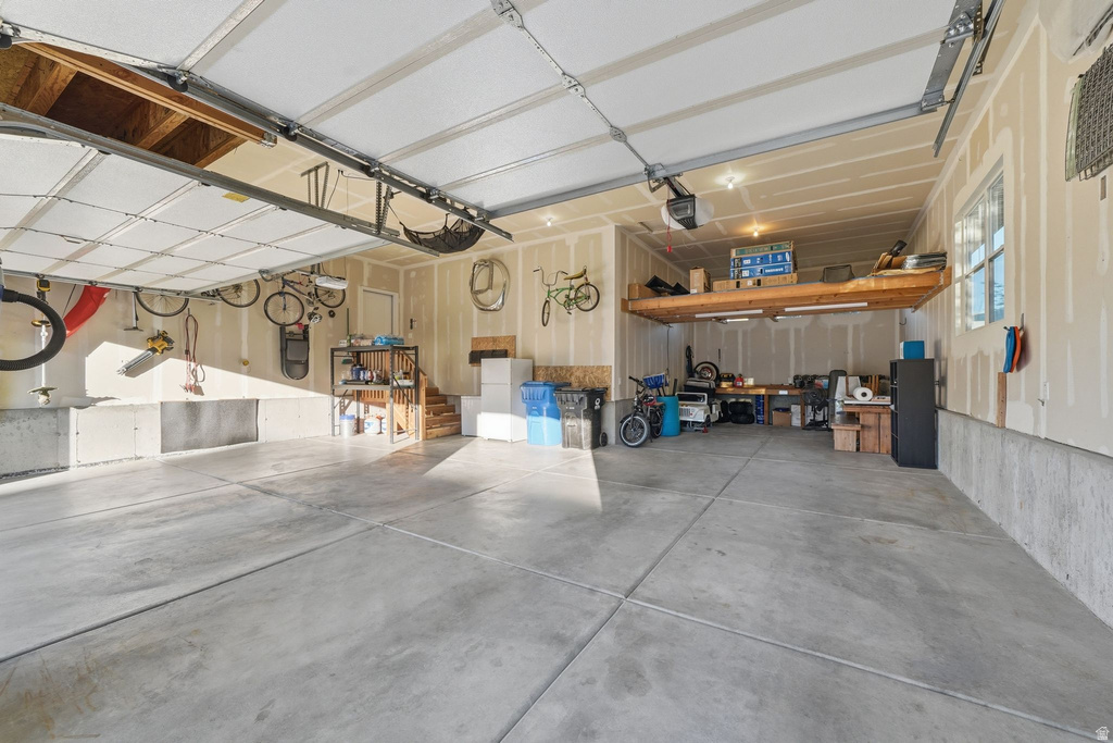 Spacious garage with concrete flooring, overhead storage platform, and an insulated garage door