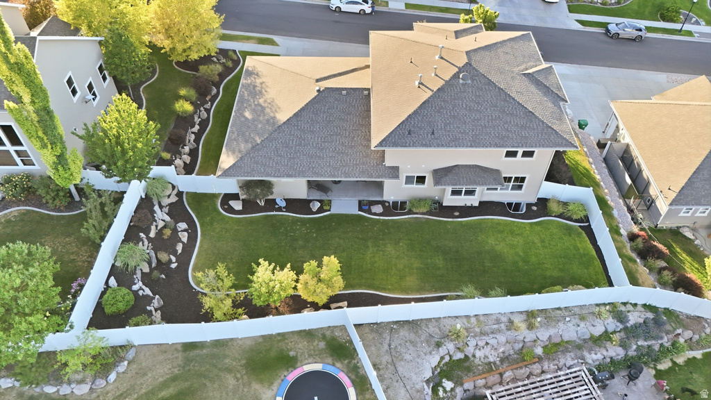 Expansive backyard featuring a manicured lawn, established landscaping beds, and a white privacy fence