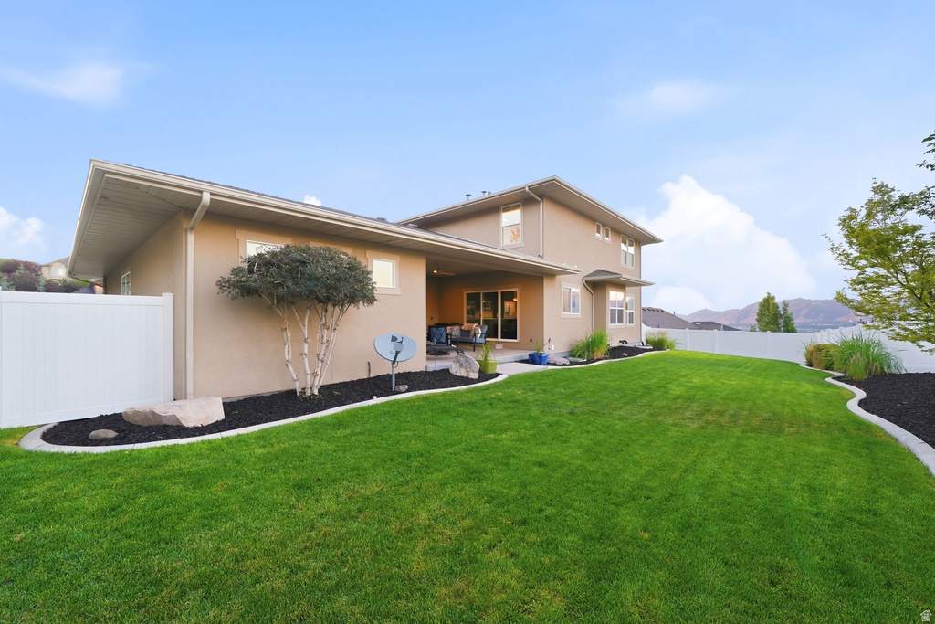 Expansive backyard featuring a manicured lawn, white vinyl fencing, and mature landscaping