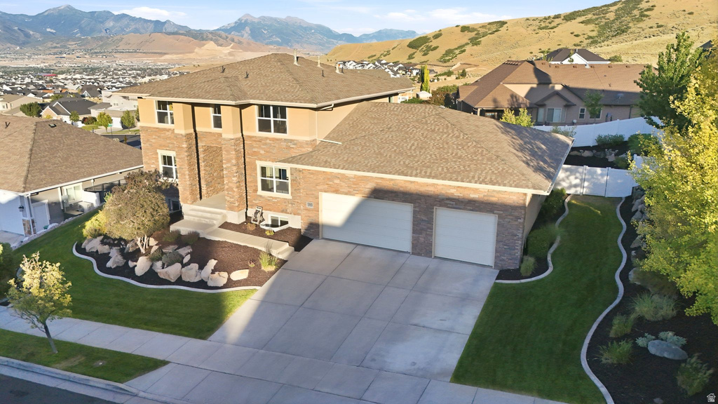 Brick and stucco exterior residence featuring a two-car garage, concrete driveway, and tiered landscaping
