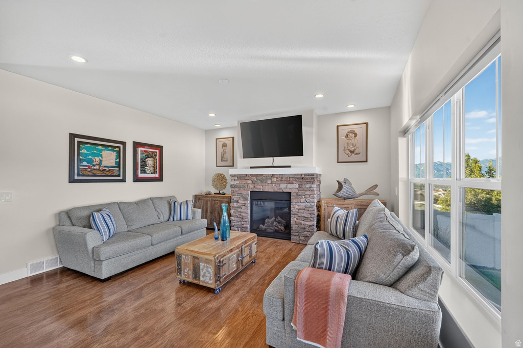 Living area featuring a floor-to-ceiling stone fireplace, recessed lighting, and wood-finish flooring