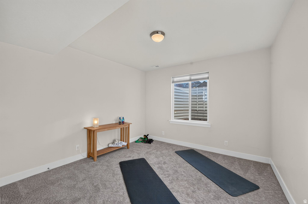 Carpeted room featuring a white-framed egress window with blinds, light neutral wall paint, and white baseboards