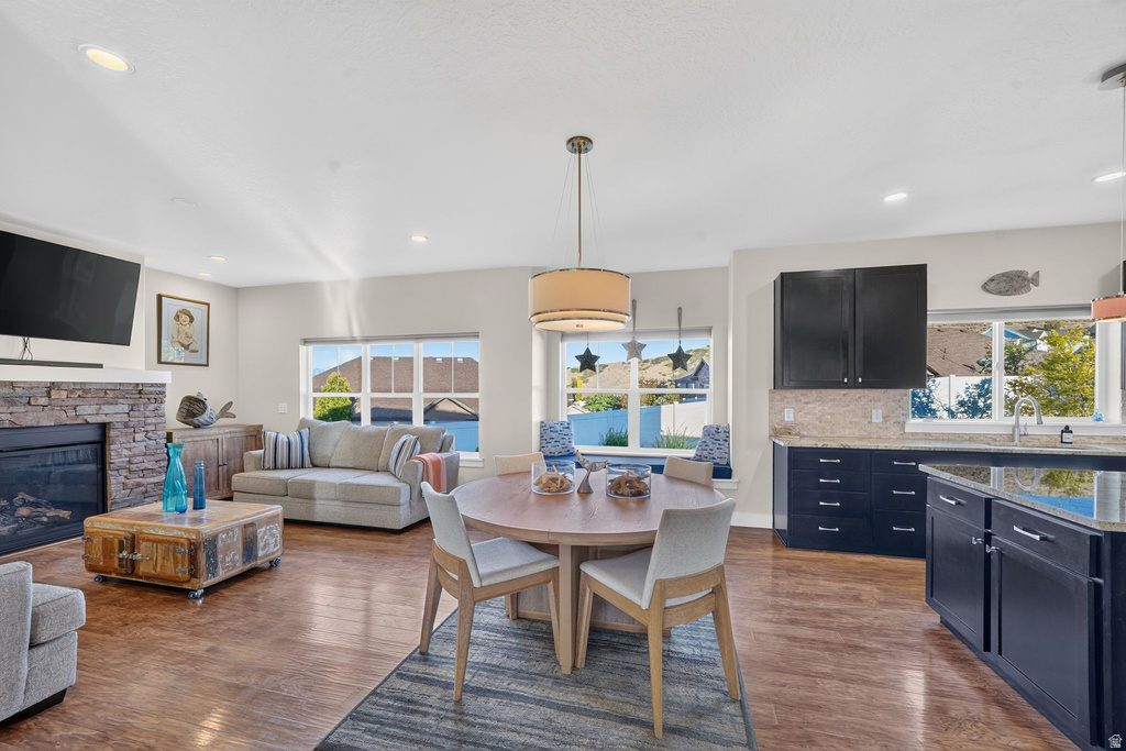 Open concept living area featuring wood-finish flooring, a stacked stone fireplace, and recessed lighting